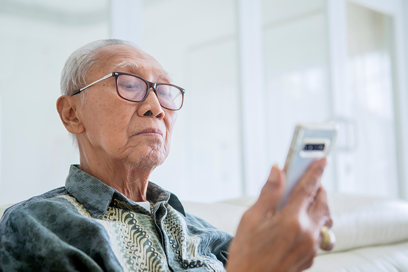 Man with ptosis having difficulty seeing his phone screen