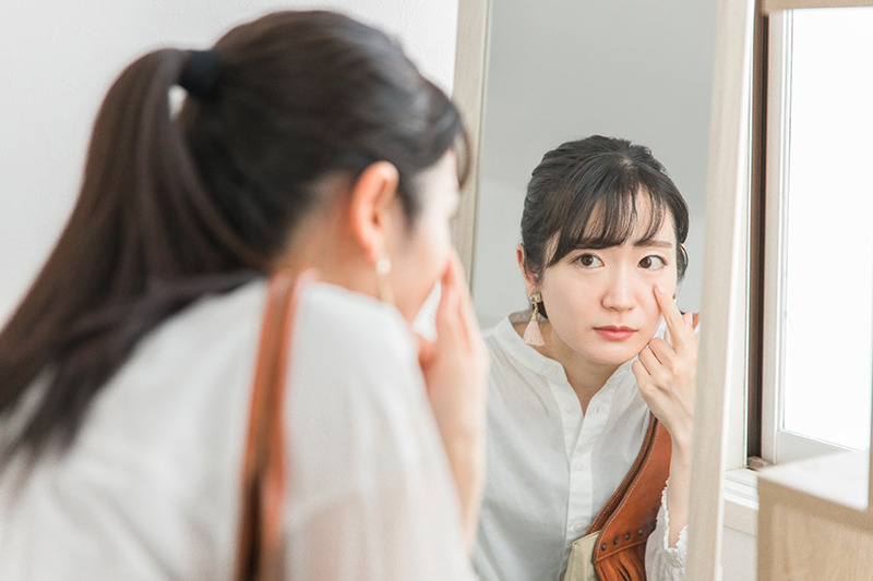 Woman looking in the mirror and noticing volume loss around her eyes